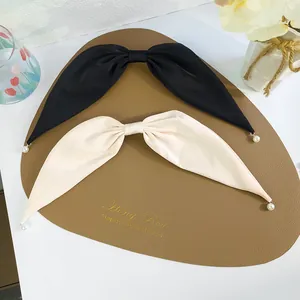 Détail de pinces à cheveux en satin avec pendentifs en perles en noir et beige crème