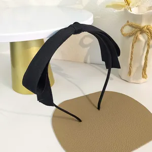 Vue détaillée d'un serre-tête noir en tissu avec nœud sur un support décoratif