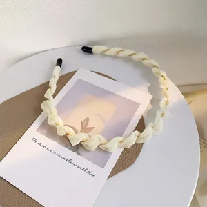 Dettaglio del cerchietto intrecciato color crema con catena dorata e punte antiscivolo