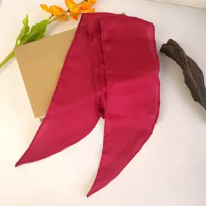 Détail d'un bandeau en satin de soie rouge rose avec extrémités pointues sur blanc