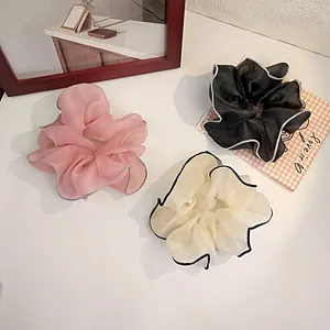 Detailed view of three large organza scrunchies in pink, white, and black with edge contrast