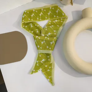 Detail of leaf pattern hair scarf in green and beige on a stylish ceramic tray
