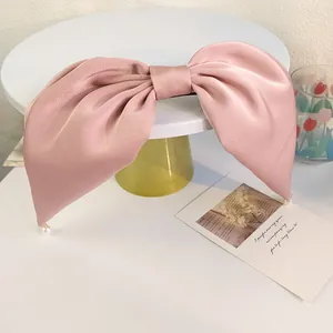 Détail d'une pince à cheveux nœud en satin rose avec perles élégantes sur plateau