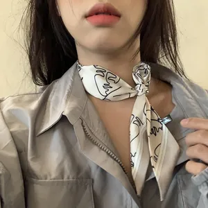 Vue détaillée d'un foulard Twilly blanc avec motif visage abstrait noué au cou