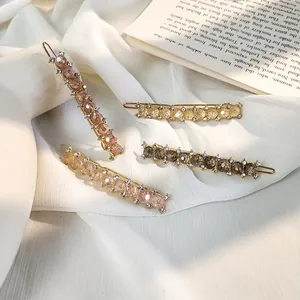 Detailed close-up of four crystal-embellished metal hair pins in various colors