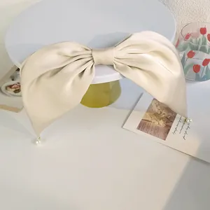 Détail d'un nœud à cheveux élégant en satin doré avec des accents de perles blanches