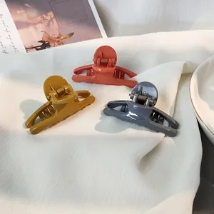 Three-piece glossy hair claw clip set in orange, yellow, and grey on white silk background