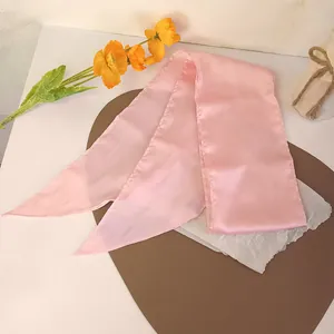 Détail d'un ruban à cheveux en satin rose cerise avec des pointes élégantes sur cuir