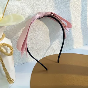 Gros plan d'un serre-tête rose avec nœud en tissu sur un support en cuir élégant
