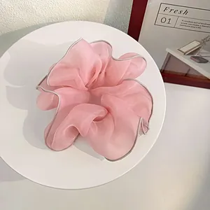 Elegant large pink organza scrunchie with silver edge detailing on a white display stand