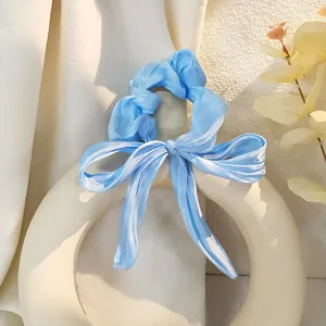 Elegante elastico per capelli in raso celeste con grande fiocco e nastri su supporto
