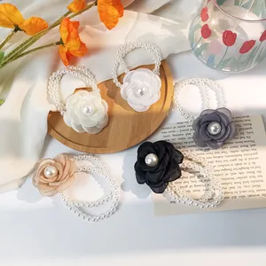 Elegant floral pearl hair ties in five colors displayed on a wooden tray with flowers
