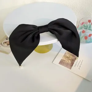 Détail d'une grande pince à cheveux nœud en satin noir avec perles blanches élégantes