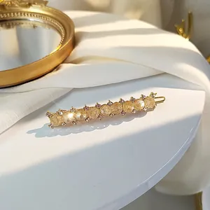 Elegant gold alloy hair clip with yellow crystals and diamonds on white surface