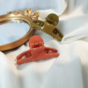 Glossy hair claw clips in coral and olive green on white fabric with vintage mirror