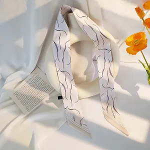 Vue détaillée d'un foulard étroit en soie avec motif abstrait sur un vase en céramique blanc