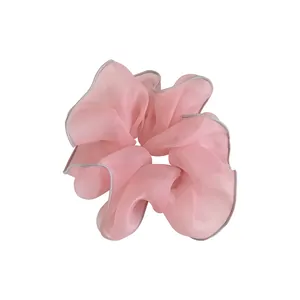 Light pink oversized organza scrunchie with silver ruffled edges in a minimalist style