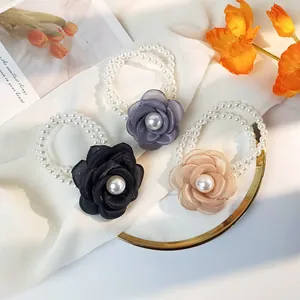 Detailed view of elegant pearl flower hair ties in black, grey, and champagne silk