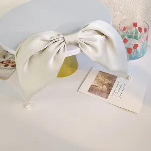 Barrette à nœud en satin champagne vintage avec perles sur un support décoratif