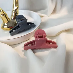 Detail of dark grey and pink glossy hair claws displayed on an elegant ceramic tray