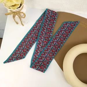 Detail of slim dark blue hair ribbon with elegant red leaf print and smooth silk texture