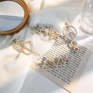 Detail of assorted pearl hair clips set with gold metal frames on white textured fabric