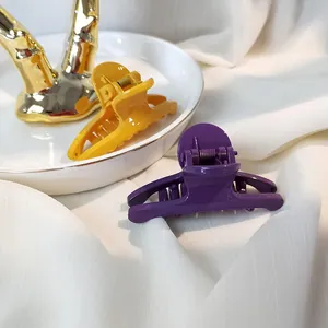 Detail view of mustard yellow and purple glossy hair claw clips on a white ceramic plate