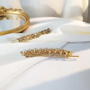 Elegant gold metal hair clips with amber crystal beads on white silk background