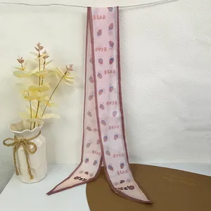Detail of light pink chiffon scarf featuring bear and strawberry patterns and BEAR text