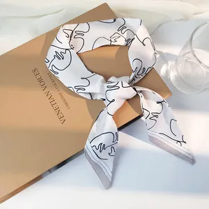 Détail d'un foulard en soie blanc avec lignes de visage sur un livre ancien