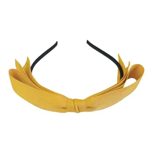 Serre-tête nœud jaune gingembre en tissu texturé sur base noire minimaliste