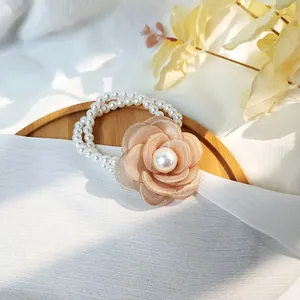 Detail of camellia flower hair tie with cream organza petals and elegant pearl beads