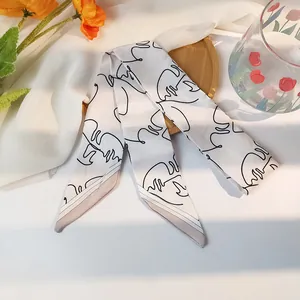 Détail d'un foulard étroit en soie avec motifs de visages minimalistes en traits noirs