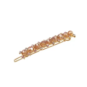 Elegant gold hair clip with amber crystal beads and pink rhinestones on white base