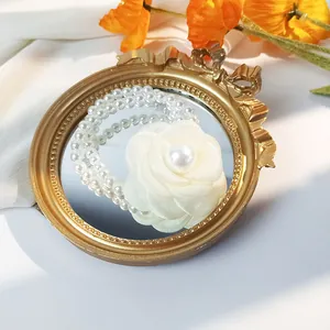 Close-up of elegant camellia flower hair tie with double-strand pearls on a gold tray