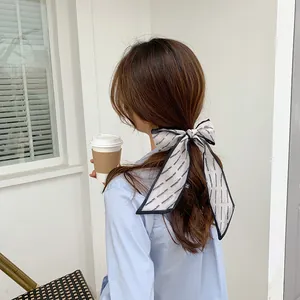 Elegant black and white printed silk hair scarf tied in a bow on a ponytail hairstyle