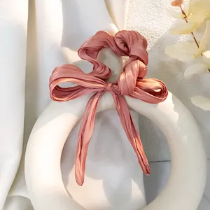 Dettaglio di elastico per capelli in raso rosa con lunghi nastri su ceramica