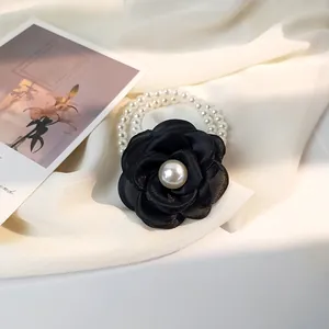 Detail of elegant black camellia fabric flower hair ring with white pearl beads