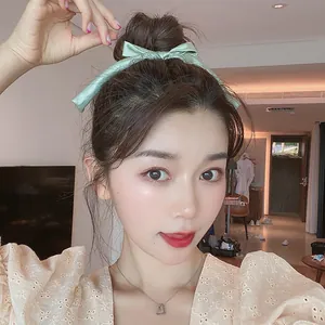Light green satin bow hair scrunchie with ribbons shown on a model for a stylish look