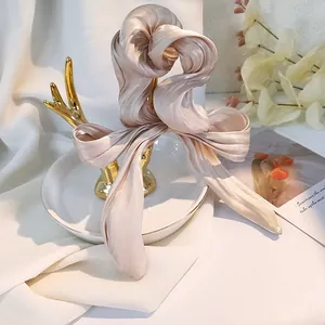 Dettaglio dell'elastico in raso champagne plissettato con nastri su supporto dorato