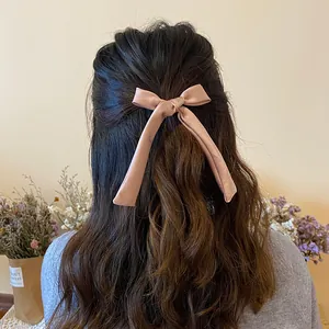 Detail of pink satin bow hair tie with long ribbons on a half-up hairstyle