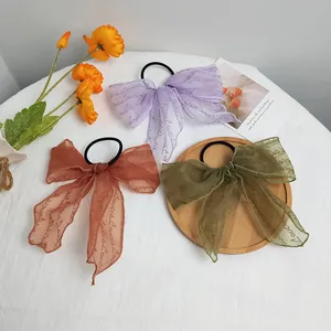 Detailed close-up of lace ribbon hair ties with vintage lettering on floral backdrop