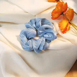 Detalle de un coletero de satén azul hielo con textura plisada en tela blanca