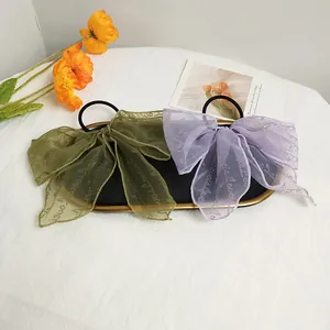 Close-up of mesh bow hair ties in dark green and lilac with Love pattern prints