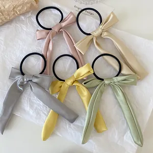 Detail of five silk ribbon bow hair ties in assorted Morandi colors on white paper