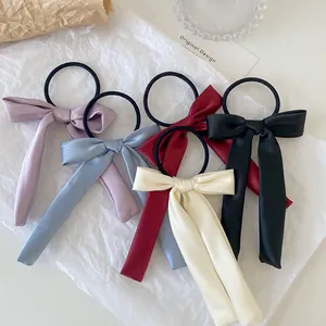 Detail of five assorted satin bow hair ties in lilac, blue, red, black, and ivory colors
