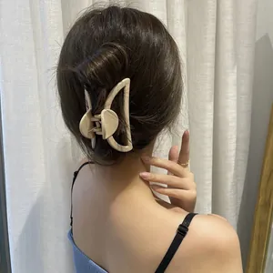 Detail of cream large hair claw clip with heart motif worn on hair for styling