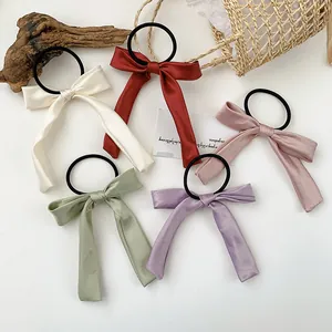 Set of five elegant satin bow hair scrunchies in pastel tones on a minimalist background