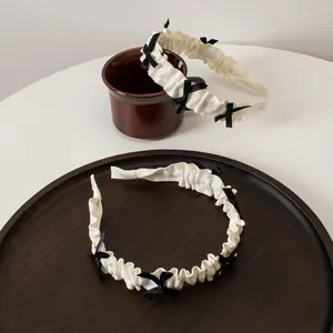 Détail de serre-têtes en tissu plissé avec petits nœuds noirs et dentelle élégante