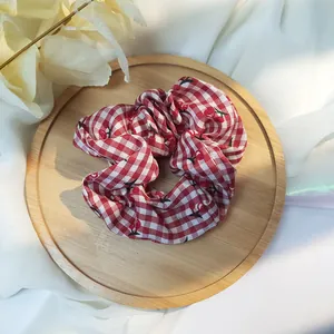 Dettaglio di scrunchie a quadretti rossi con ciliegie su un vassoio di legno rustico